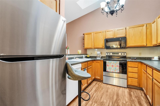 kitchen with tasteful backsplash, sink, stainless steel appliances, and vaulted ceiling with skylight