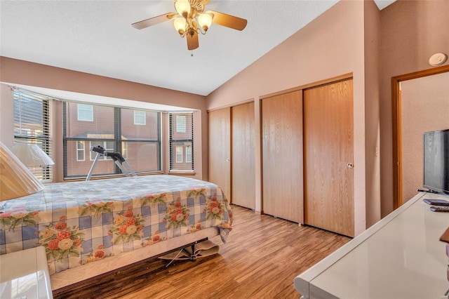 bedroom with lofted ceiling, two closets, light hardwood / wood-style floors, and ceiling fan