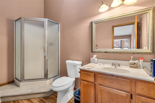 bathroom featuring vanity, hardwood / wood-style floors, a shower with door, and toilet