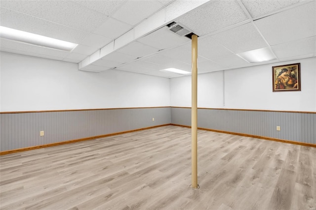 basement with a paneled ceiling and light hardwood / wood-style floors