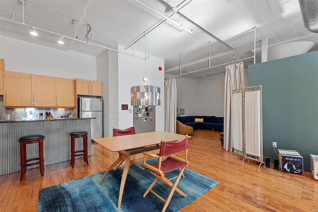 dining room with light hardwood / wood-style flooring, rail lighting, and a high ceiling