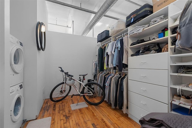 walk in closet featuring wood-type flooring and stacked washer / drying machine