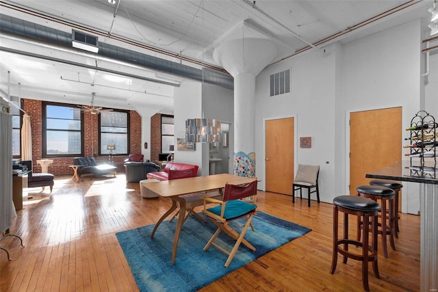 dining space with brick wall, hardwood / wood-style floors, and a high ceiling