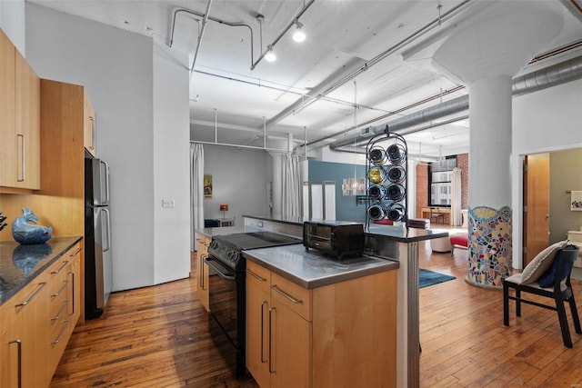 kitchen featuring rail lighting, stainless steel counters, black / electric stove, stainless steel fridge, and dark hardwood / wood-style flooring