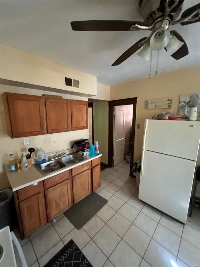 kitchen featuring sink, light tile patterned floors, ceiling fan, and white refrigerator