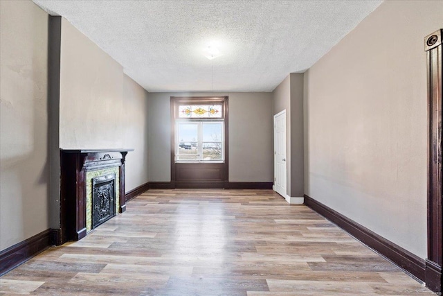 unfurnished living room featuring a textured ceiling and light hardwood / wood-style floors