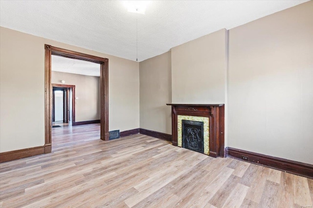 unfurnished living room featuring a textured ceiling and light hardwood / wood-style flooring