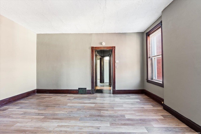 unfurnished room featuring light hardwood / wood-style flooring and a textured ceiling