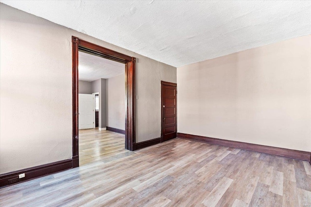 spare room with a textured ceiling and light wood-type flooring