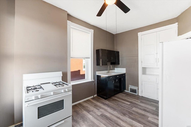 kitchen featuring ceiling fan, white appliances, sink, and light hardwood / wood-style flooring