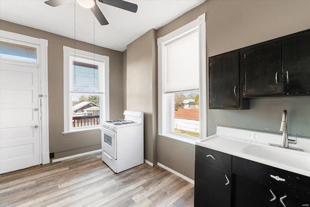 kitchen with sink, ceiling fan, light hardwood / wood-style floors, white range with gas cooktop, and decorative light fixtures