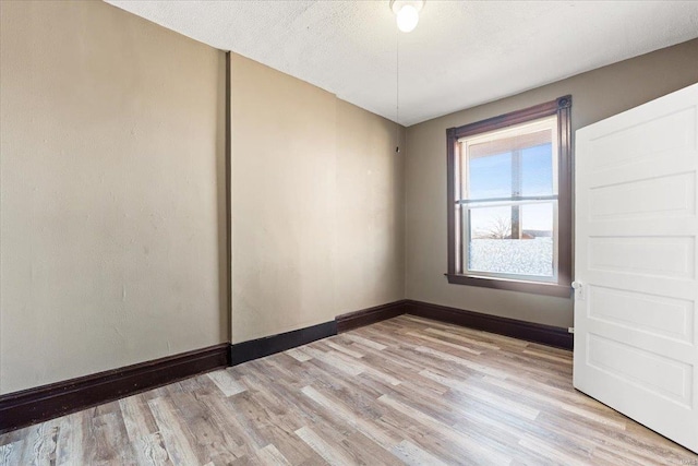 empty room with light hardwood / wood-style floors and a textured ceiling