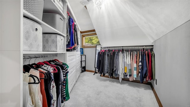 walk in closet with light carpet and vaulted ceiling