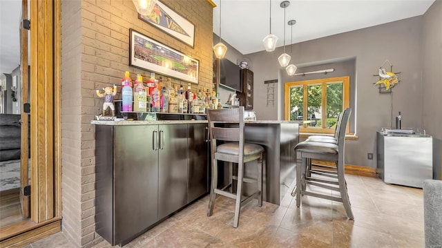 bar featuring brick wall, dark brown cabinetry, hanging light fixtures, and light tile patterned floors