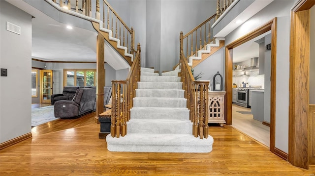 stairway featuring crown molding, sink, hardwood / wood-style flooring, and a high ceiling