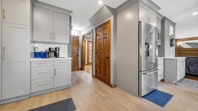 kitchen featuring gray cabinetry, high end refrigerator, and backsplash