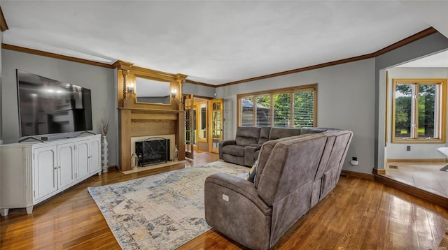 living room with crown molding, a large fireplace, and light hardwood / wood-style flooring