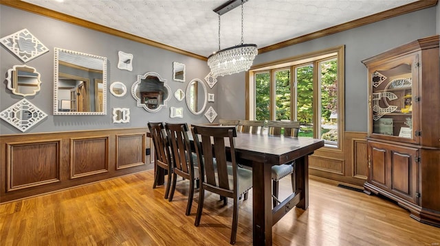 dining room featuring an inviting chandelier, light hardwood / wood-style flooring, and ornamental molding