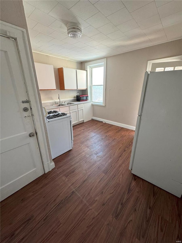 kitchen with white appliances, dark hardwood / wood-style flooring, sink, and white cabinets