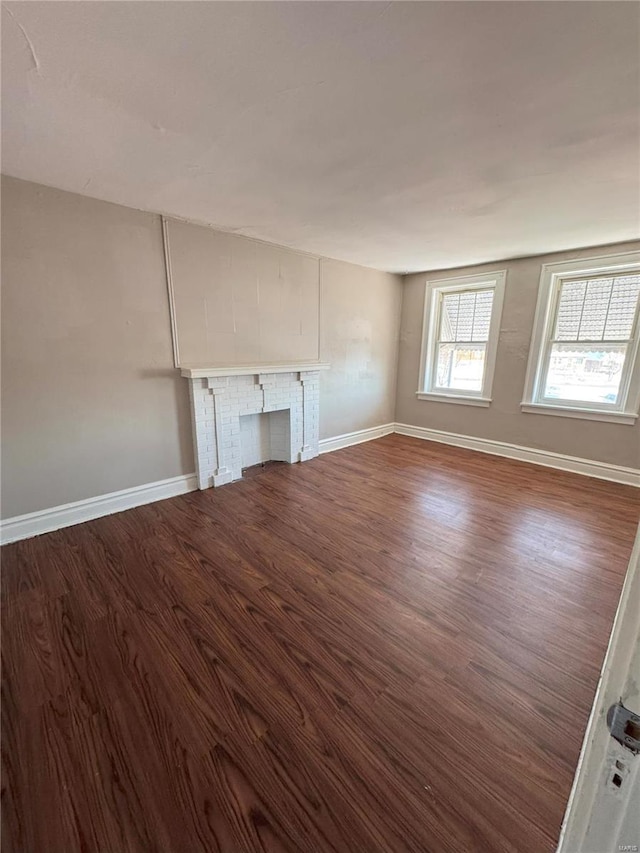 unfurnished living room with dark wood-type flooring and a fireplace