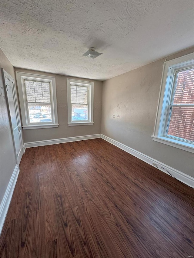 empty room featuring dark hardwood / wood-style floors and a textured ceiling