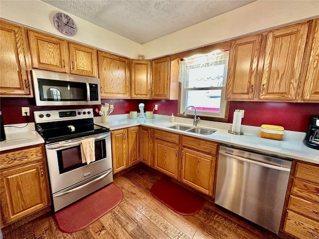 kitchen featuring sink, stainless steel appliances, hardwood / wood-style floors, and a textured ceiling