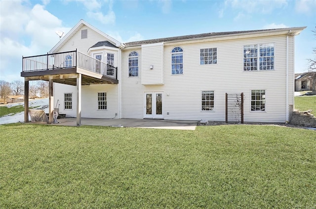 rear view of property with a wooden deck, a lawn, and a patio