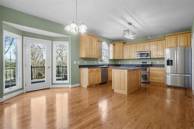 kitchen featuring pendant lighting, light hardwood / wood-style flooring, stainless steel appliances, and a kitchen island