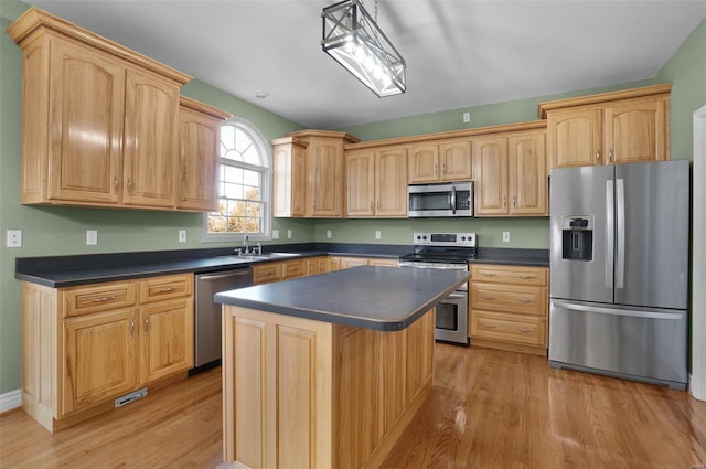 kitchen with pendant lighting, appliances with stainless steel finishes, a center island, and light hardwood / wood-style floors