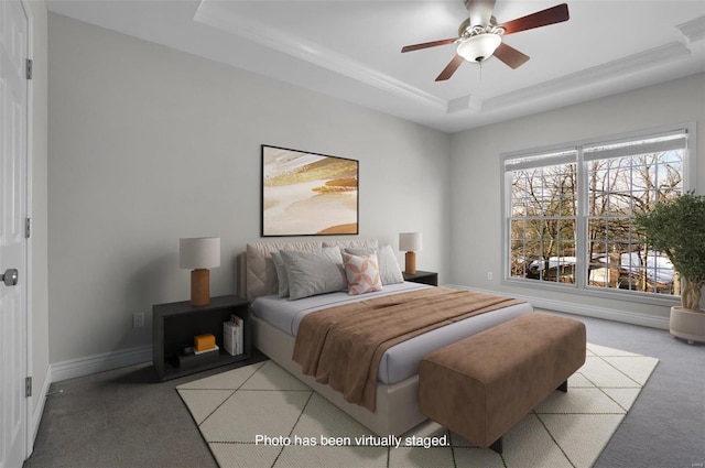 carpeted bedroom featuring multiple windows, ceiling fan, and a tray ceiling