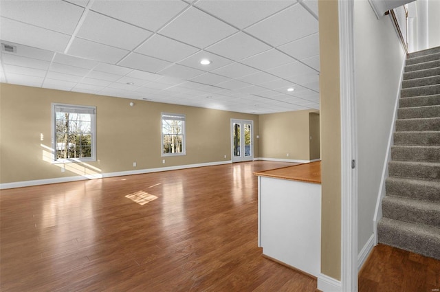 unfurnished living room featuring hardwood / wood-style flooring and a drop ceiling