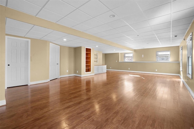 interior space featuring hardwood / wood-style flooring, a paneled ceiling, and built in features