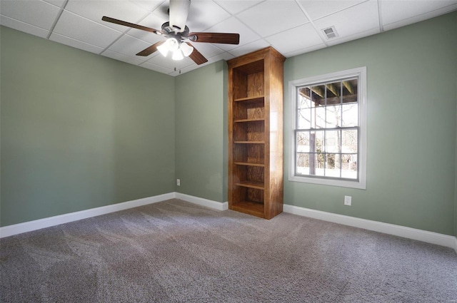 carpeted empty room with ceiling fan and a drop ceiling