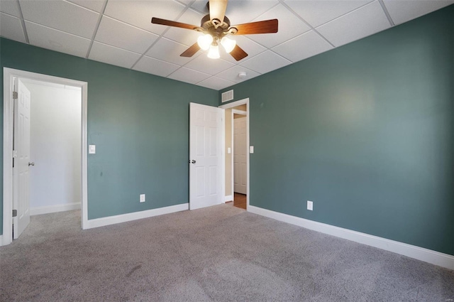 carpeted empty room featuring ceiling fan and a drop ceiling