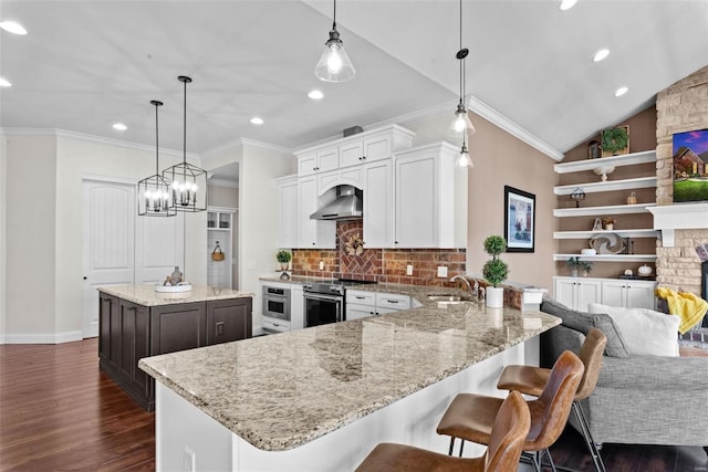 kitchen featuring decorative light fixtures, sink, a center island, stainless steel appliances, and wall chimney range hood