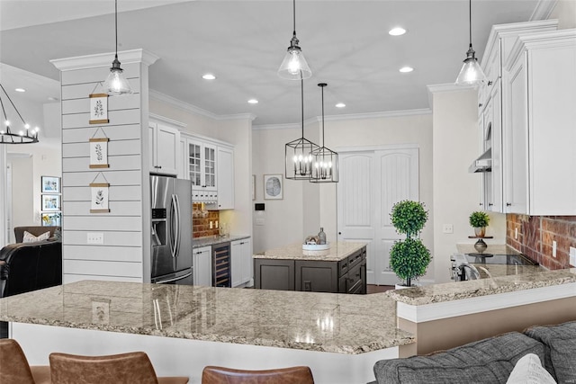 kitchen with a breakfast bar, a center island, stainless steel fridge with ice dispenser, hanging light fixtures, and kitchen peninsula