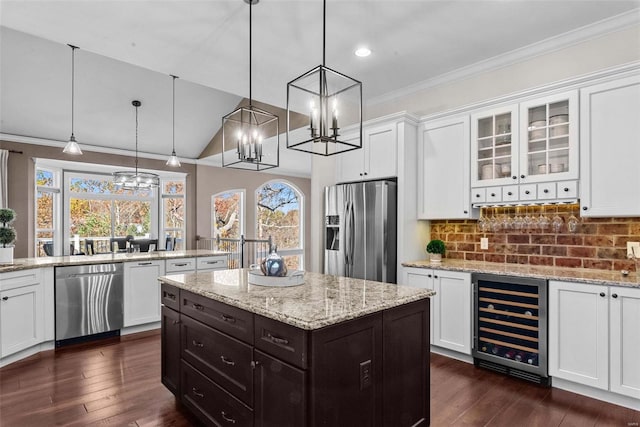 kitchen with a kitchen island, appliances with stainless steel finishes, decorative light fixtures, white cabinets, and beverage cooler