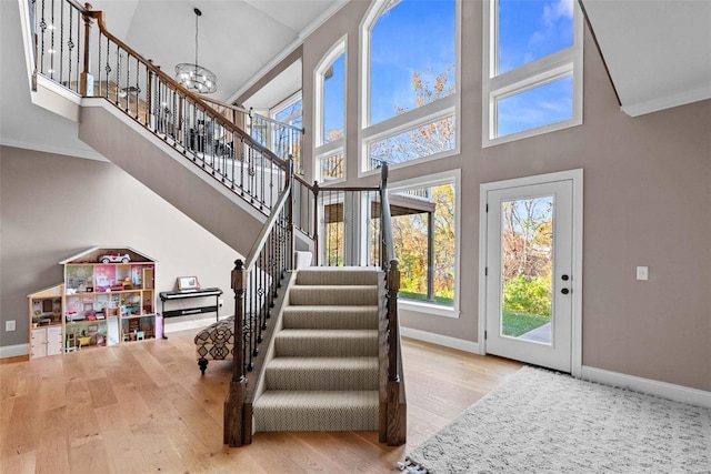 stairs with hardwood / wood-style floors, a chandelier, and a high ceiling