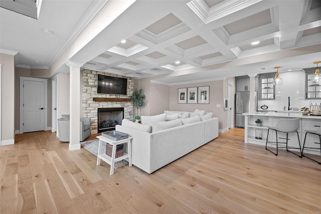 living room with crown molding, coffered ceiling, a large fireplace, beamed ceiling, and light wood-type flooring