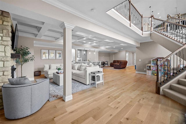 living room with coffered ceiling, crown molding, and light hardwood / wood-style flooring