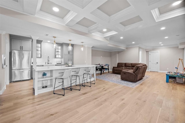 living room featuring coffered ceiling, beam ceiling, ornamental molding, and light wood-type flooring