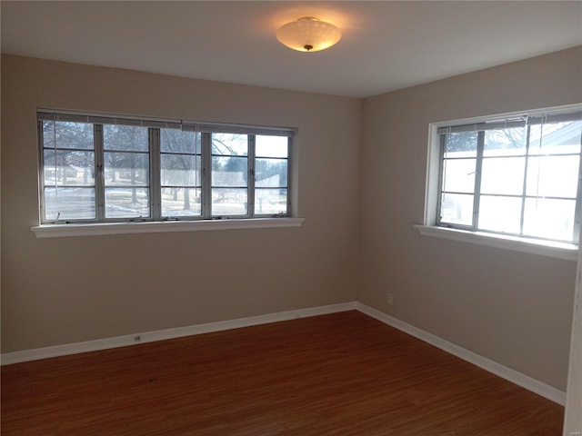 empty room featuring dark wood-type flooring and a healthy amount of sunlight