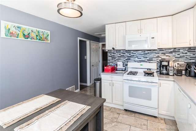 kitchen with tasteful backsplash, white appliances, white cabinets, and light tile patterned flooring