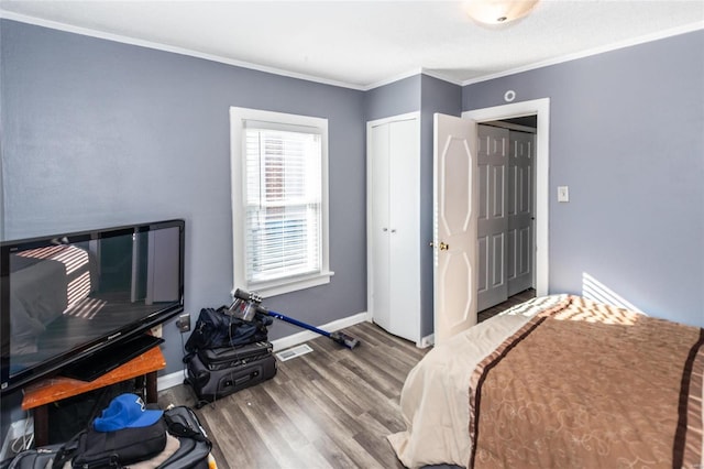 bedroom with hardwood / wood-style flooring, crown molding, and a closet