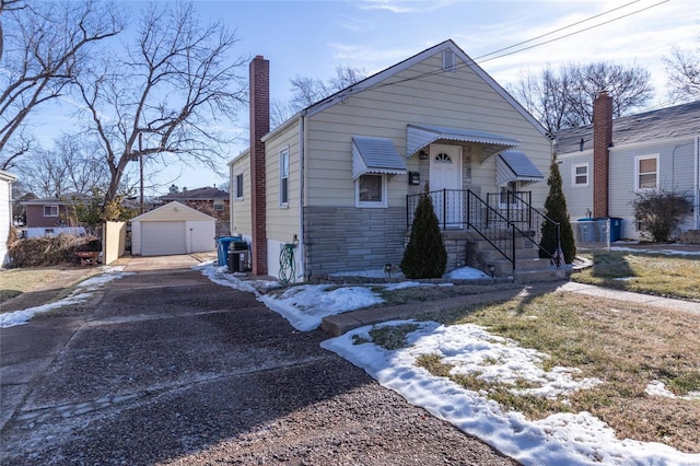 bungalow-style house featuring a garage, central AC, and an outbuilding