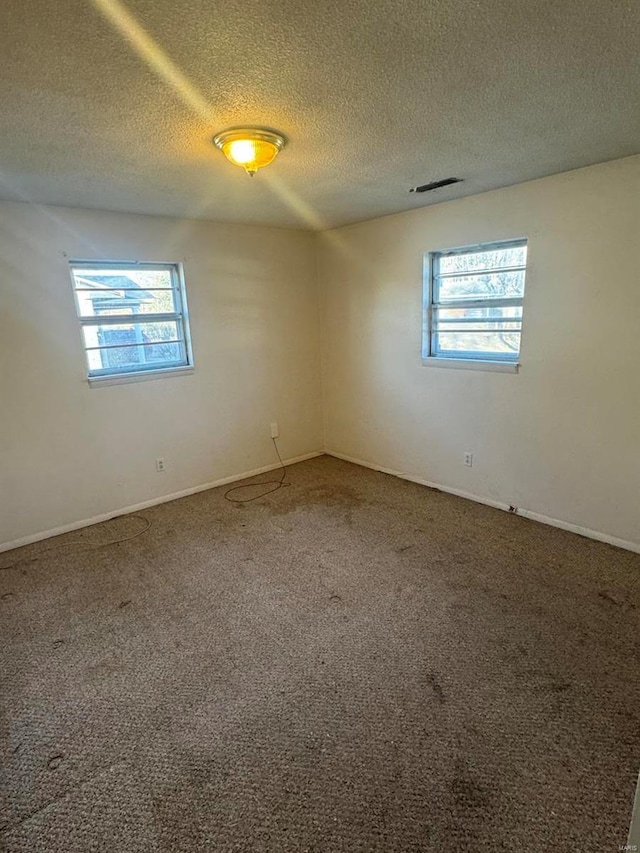 carpeted empty room featuring a textured ceiling