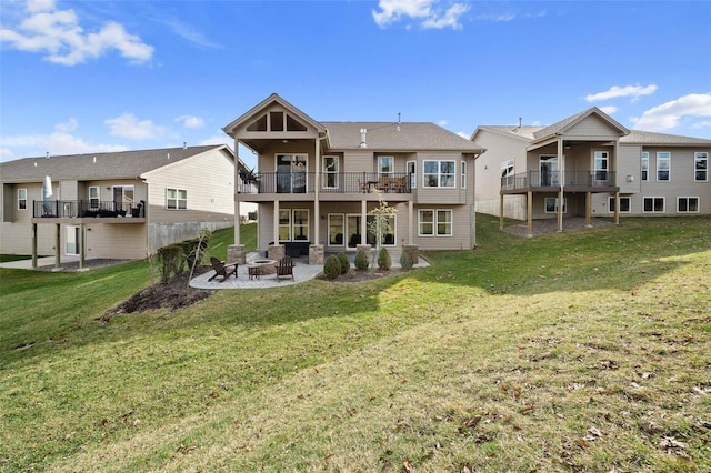 back of house featuring a fire pit, a yard, a patio, and a balcony