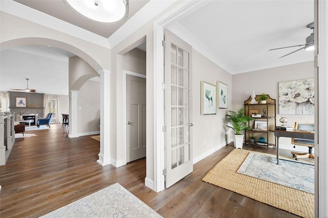 office space featuring dark wood-type flooring, ornamental molding, ceiling fan, and ornate columns