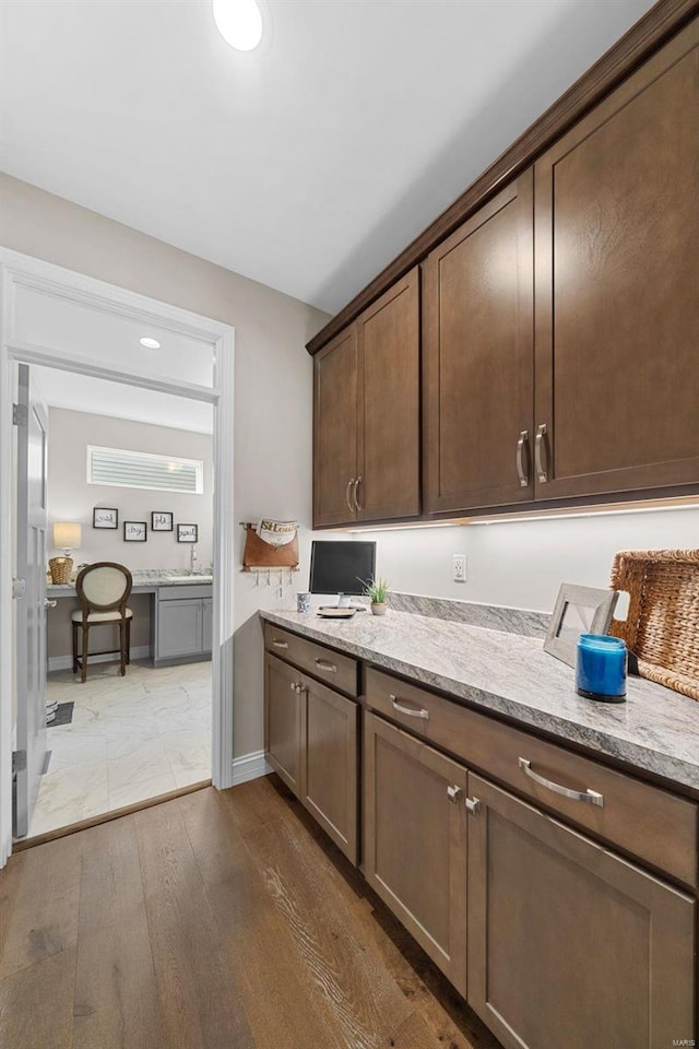 kitchen with light stone counters, dark brown cabinetry, and dark hardwood / wood-style flooring