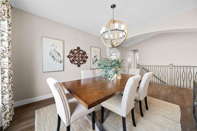 dining space featuring lofted ceiling, dark wood-type flooring, and an inviting chandelier